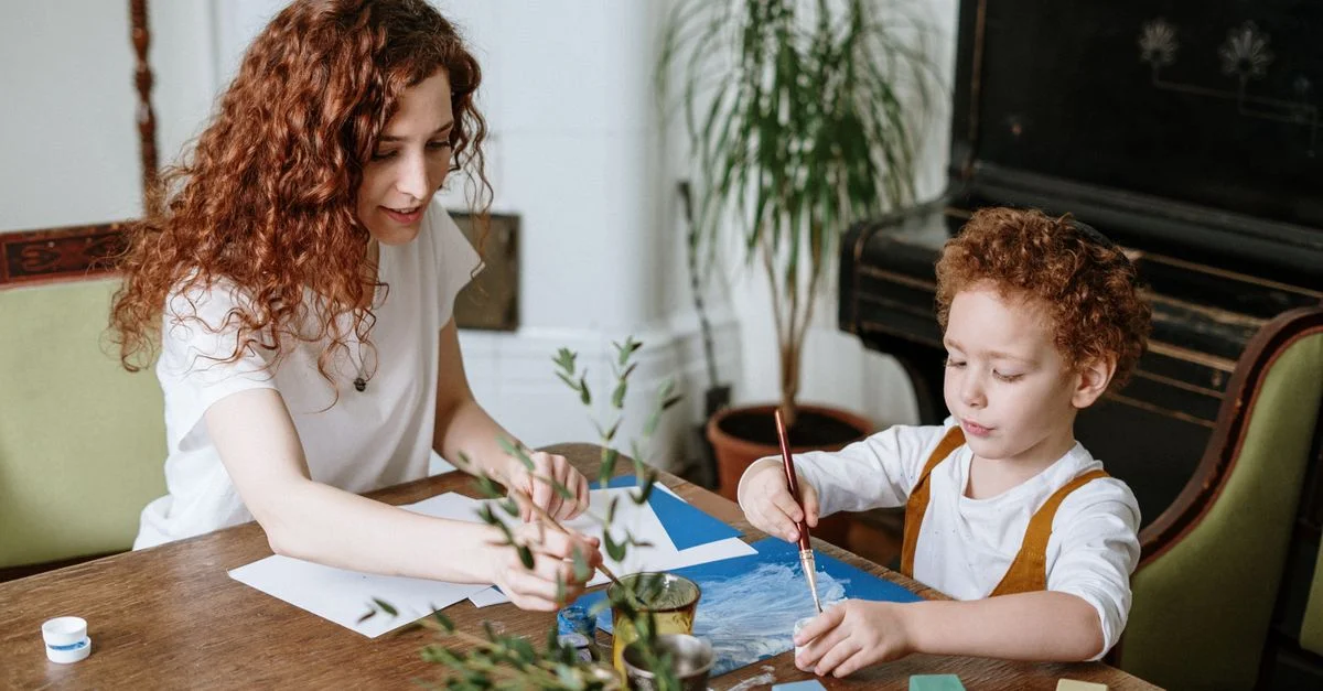 Une mère et son fils peignent ensemble à la maison, favorisant la créativité et les liens.