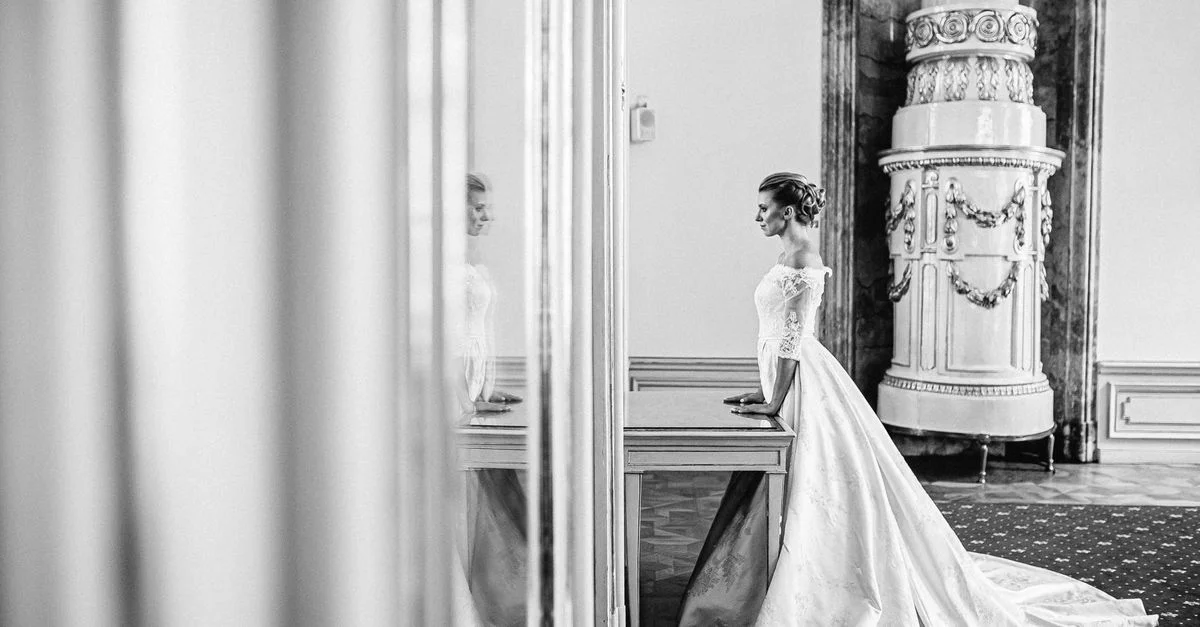 Photo en noir et blanc d'une mariée dans une élégante robe de mariage dans un espace intérieur vintage.