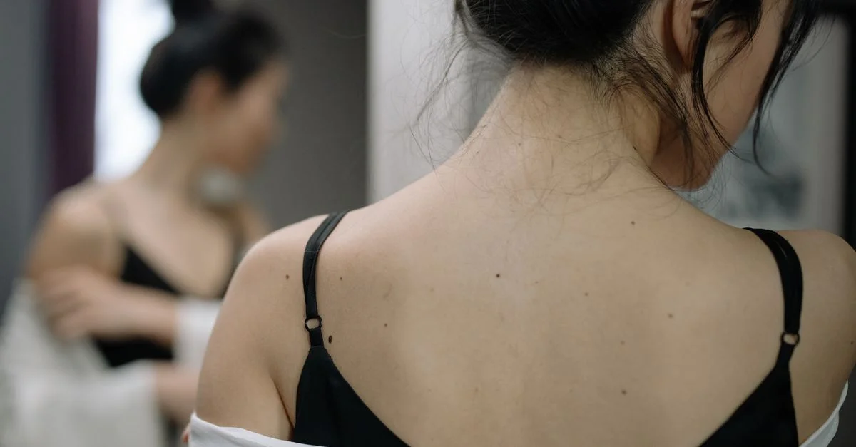 Prise de vue en gros plan d'une femme ajustant sa blouse devant un miroir avec un arrière-plan flou.