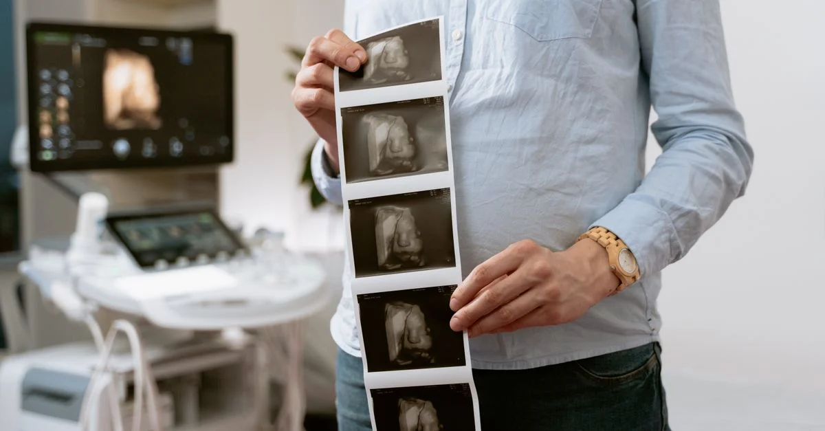 Une personne tenant des images d'échographie dans une clinique médicale, illustrant le suivi de la grossesse.