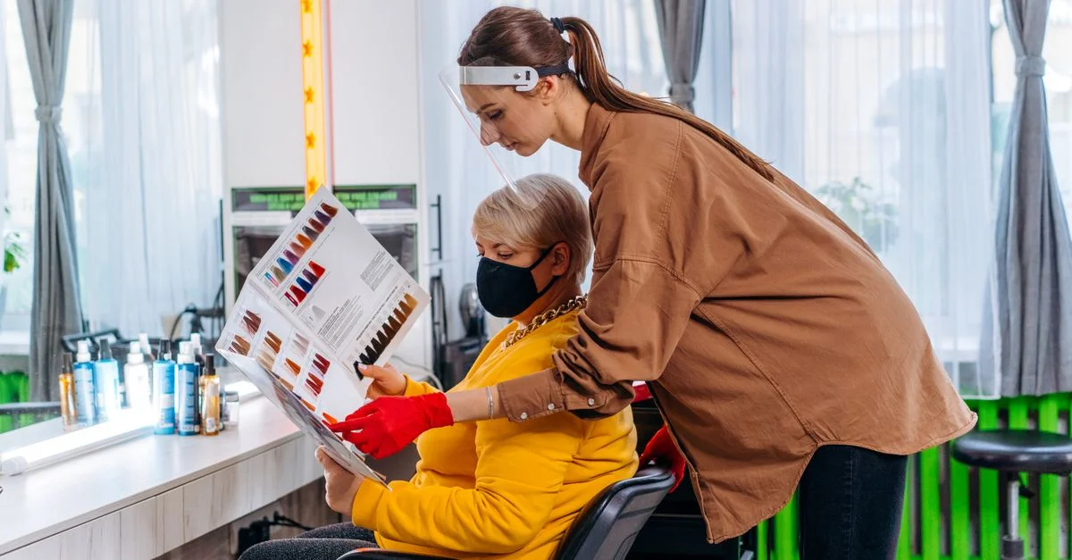 Coiffeur aidant un client à choisir la couleur de cheveux dans un salon moderne.