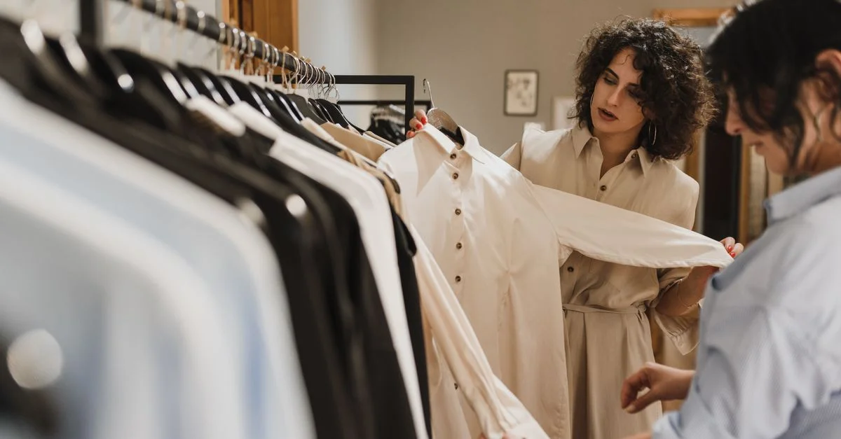 Deux femmes sélectionnant soigneusement des vêtements sur un porte-vêtements dans une boutique élégante.