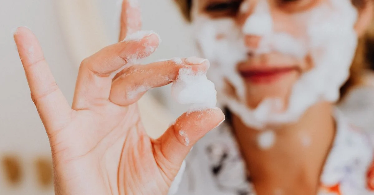 Gros plan d'une femme utilisant de la mousse nettoyante pour le visage, mettant en avant sa routine de soins de la peau.