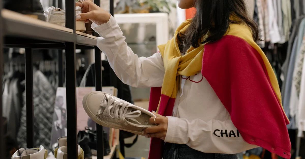 Une femme parcourant des baskets dans un magasin d'occasion, mettant en avant l'expérience de shopping.