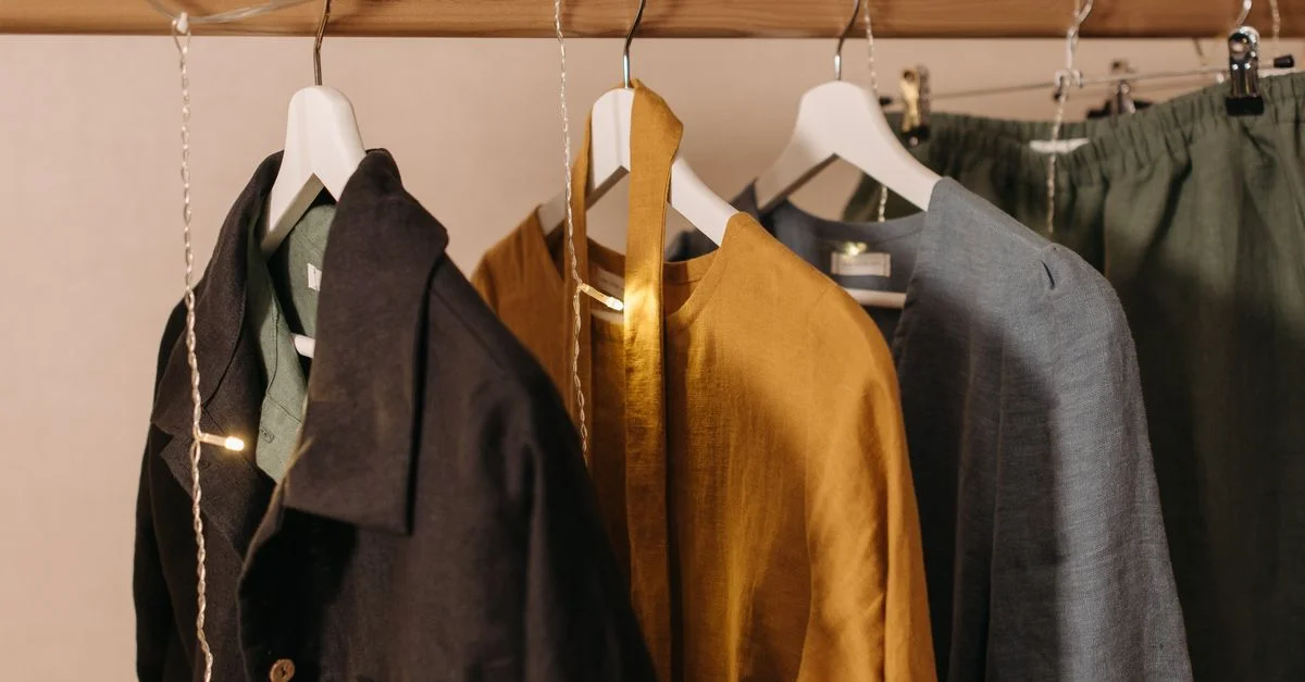 Gros plan de vêtements à la mode accrochés sur un rack en bois avec des lumières à filament.
