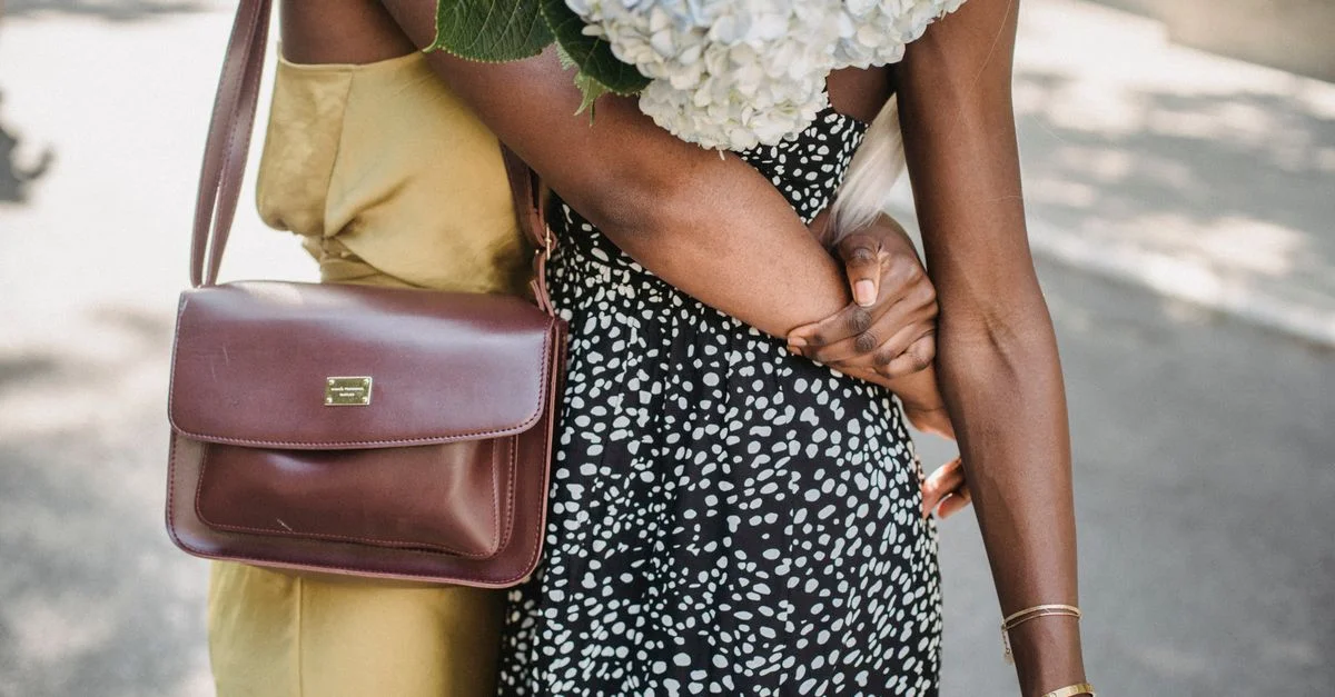 Gros plan de deux femmes s'enlaçant avec un bouquet d'hortensias en plein air, montrant l'amitié et l'unité.