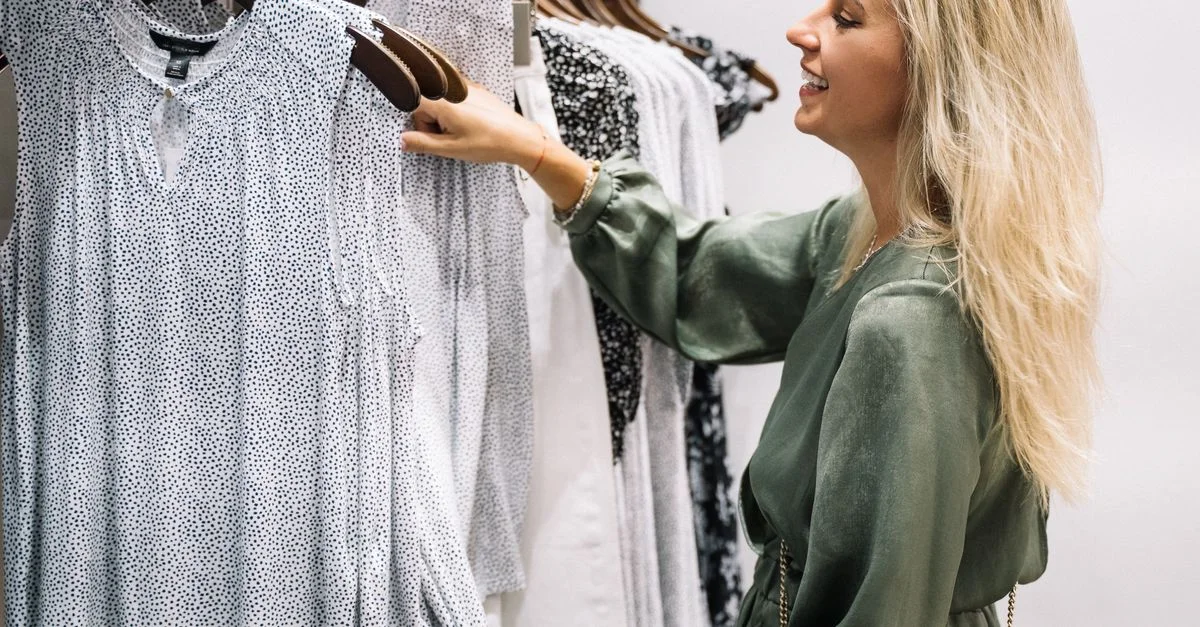 Femme souriante examinant des options de vêtements élégants dans un dressing moderne.