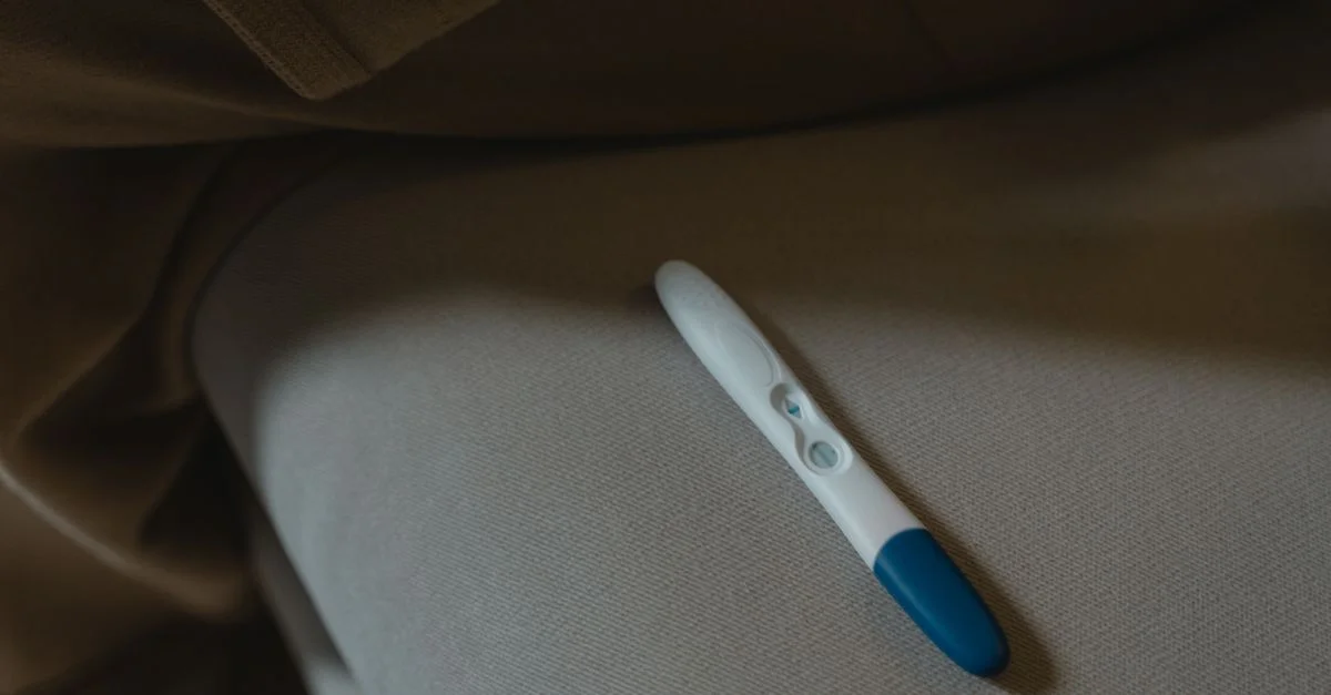 Une image en gros plan d'un test de grossesse reposant sur une surface en tissu doux, symbolisant l'anticipation et les nouveaux départs.