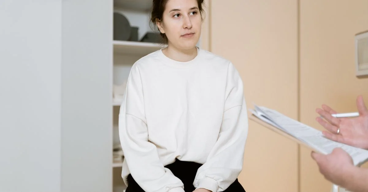 Femme adulte assise attentivement pendant une consultation médicale à l'intérieur d'une clinique.