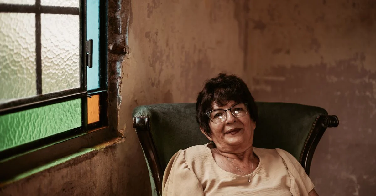 Une femme âgée assise dans un fauteuil confortable près d'un vitrail à Buenos Aires.