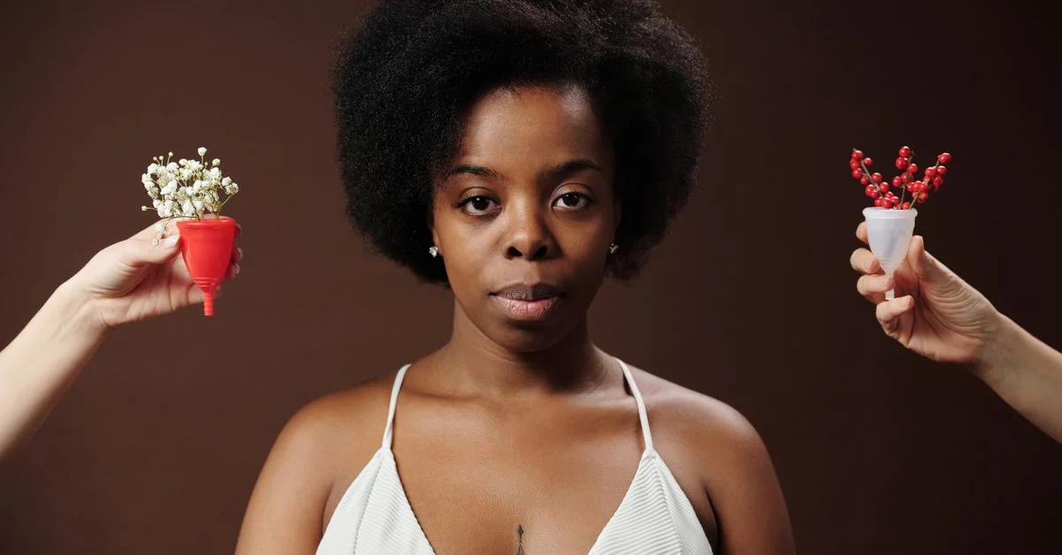 Portrait d'une femme tenant des coupes menstruelles symbolisant la féminité et l'autonomisation.