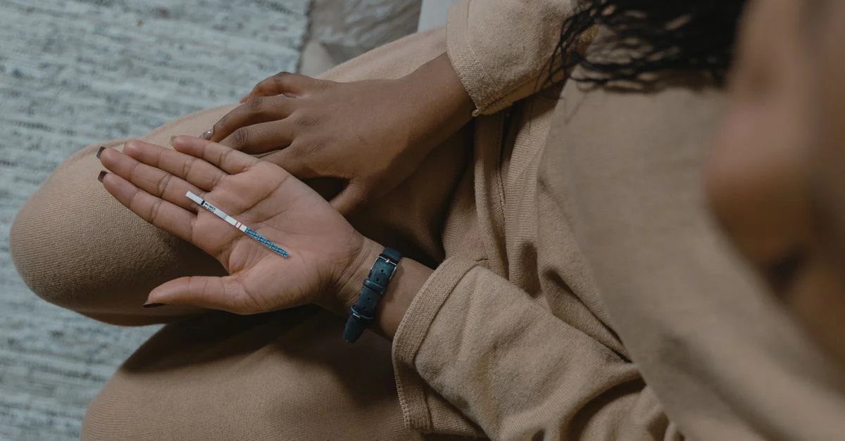Un adulte avec un test de grossesse en main, exprimant de l'anticipation et de l'espoir.
