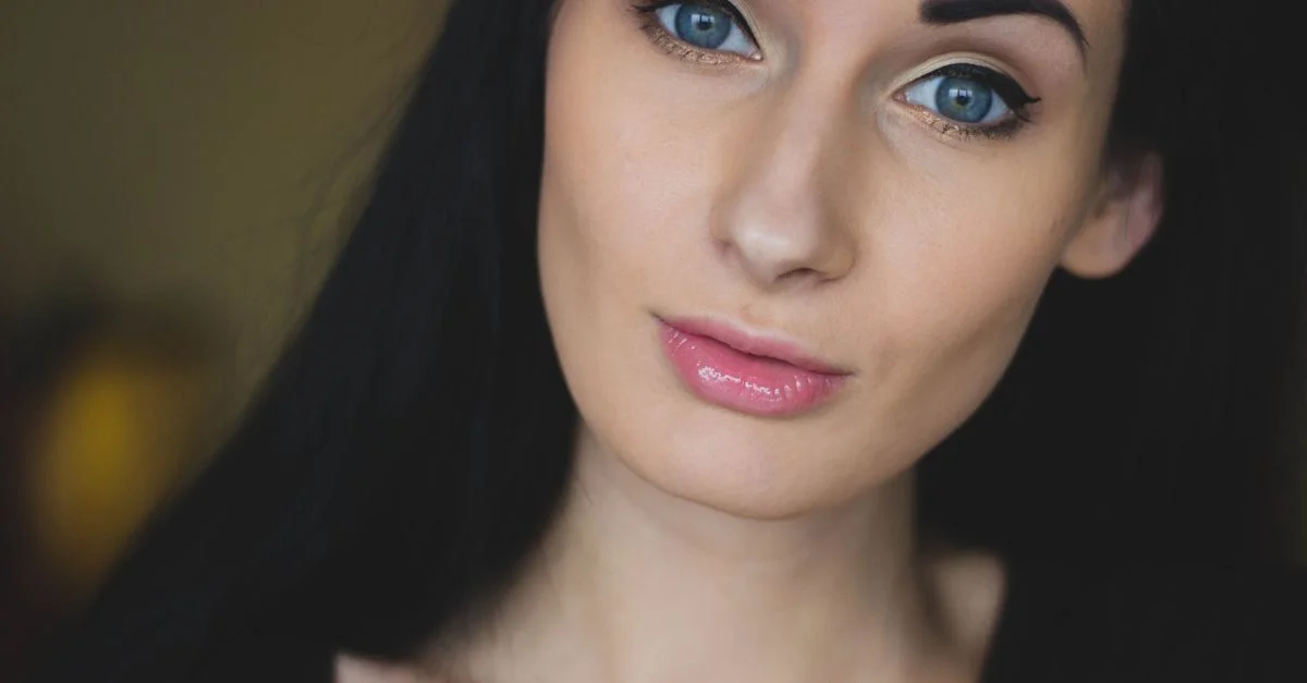 Un portrait en gros plan frappant d'une jeune femme aux yeux bleus éclatants et aux cheveux noirs.