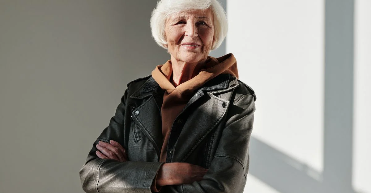 Une femme senior dégage confiance et style dans une veste en cuir noir avec un sourire chaleureux.