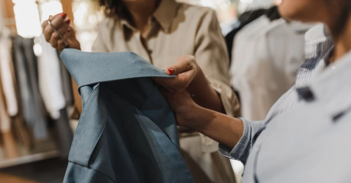 Des femmes examinant un vêtement bleu dans une boutique moderne, mettant en avant une expérience de shopping.