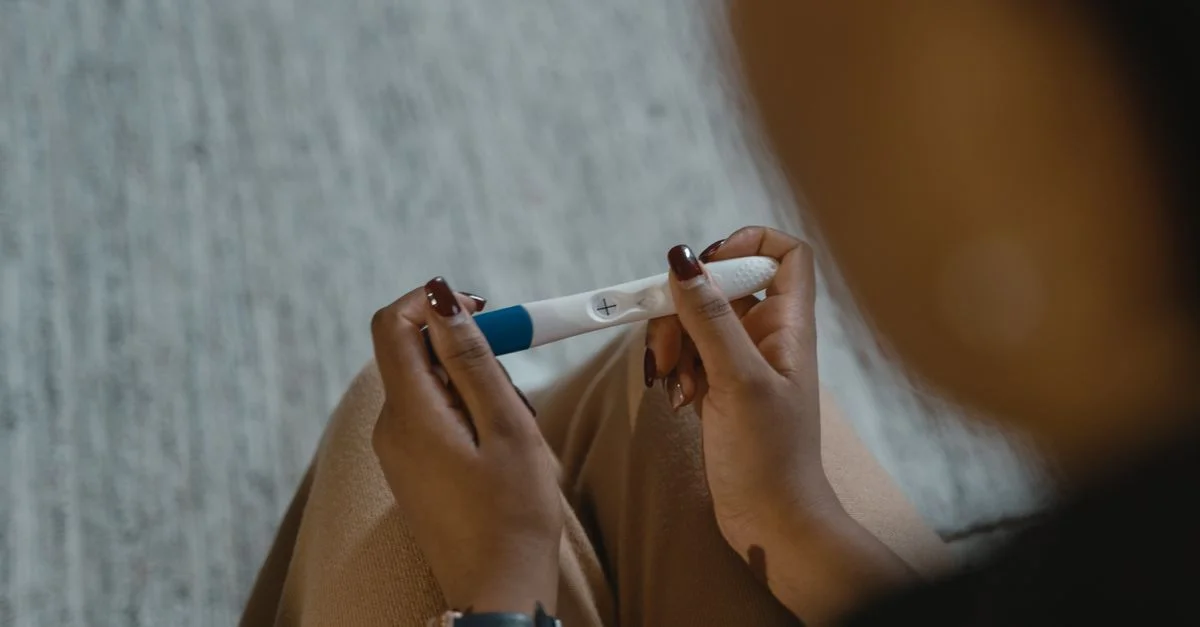 Gros plan sur une femme tenant un test de grossesse positif avec un signe plus, symbolisant de nouveaux commencements.