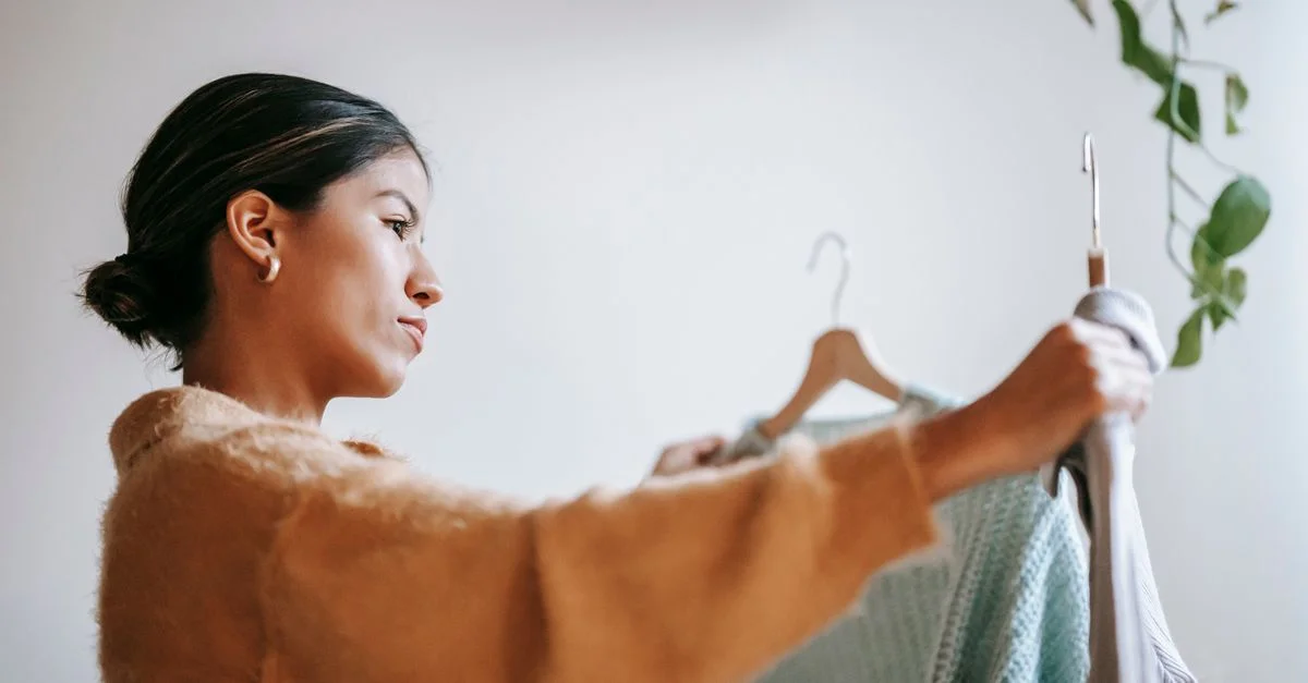 Vue de côté d'une femme sélectionnant des vêtements dans une boutique avec un accent sur le style et le choix.