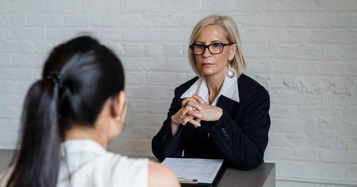 Femme d'affaires professionnelle en blazer noir menant une interview à l'intérieur.