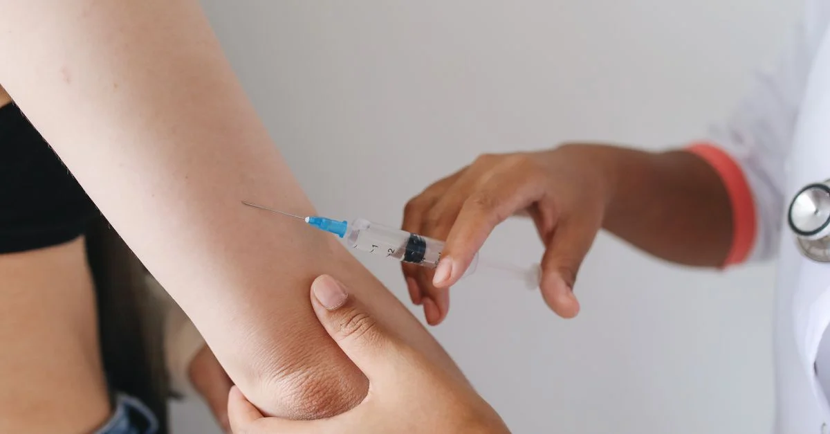 Médecin administrant une injection dans le bras d'un patient, vue en gros plan.