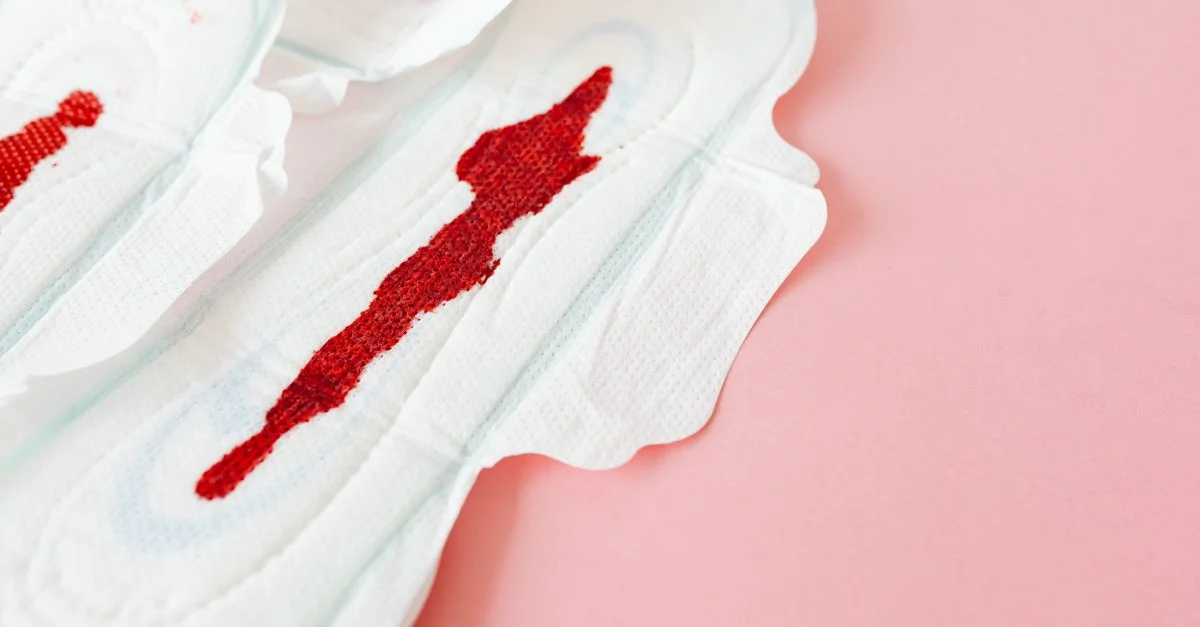 Gros plan sur des serviettes menstruelles tachées sur une surface rose mettant en avant la santé des femmes et la menstruation.